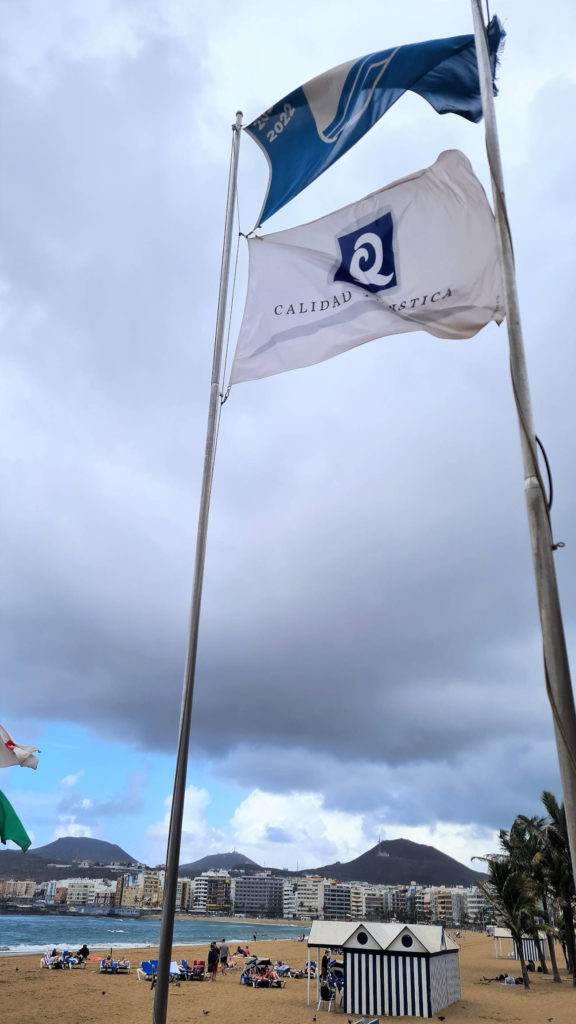 Q Siegels vom Calidad Turística Española weht neben der Blaue Flagge am Strand Playa de Las Canteras Gran Canaria